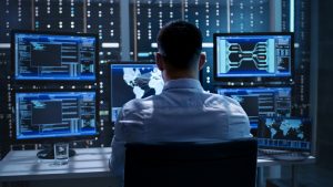 System Security Specialist Working at System Control Center evaluates synthetic monitoring vs. real user monitoring, zero-day attacks, vulnerability management, cybersecurity awareness month, cybersecurity best practices, Apache Commons Text vulnerability